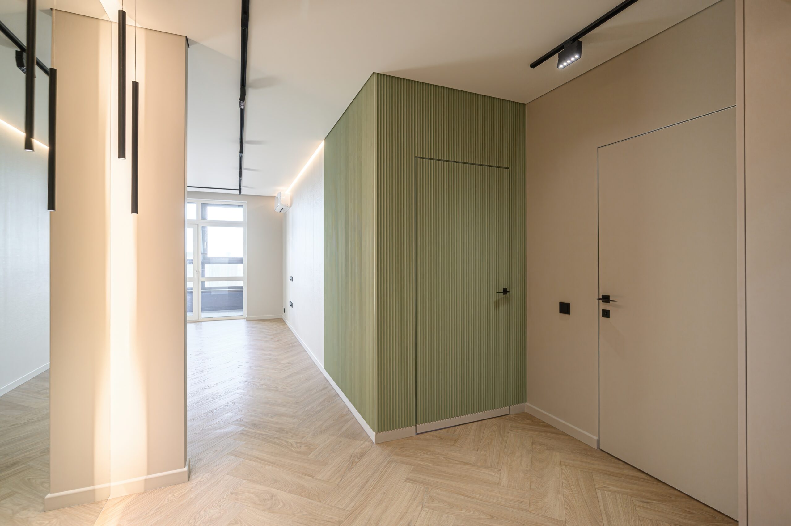 A sleek, modern interior featuring frameless flush doors that blend seamlessly into beige and green accent walls, creating a minimalist, cohesive look.