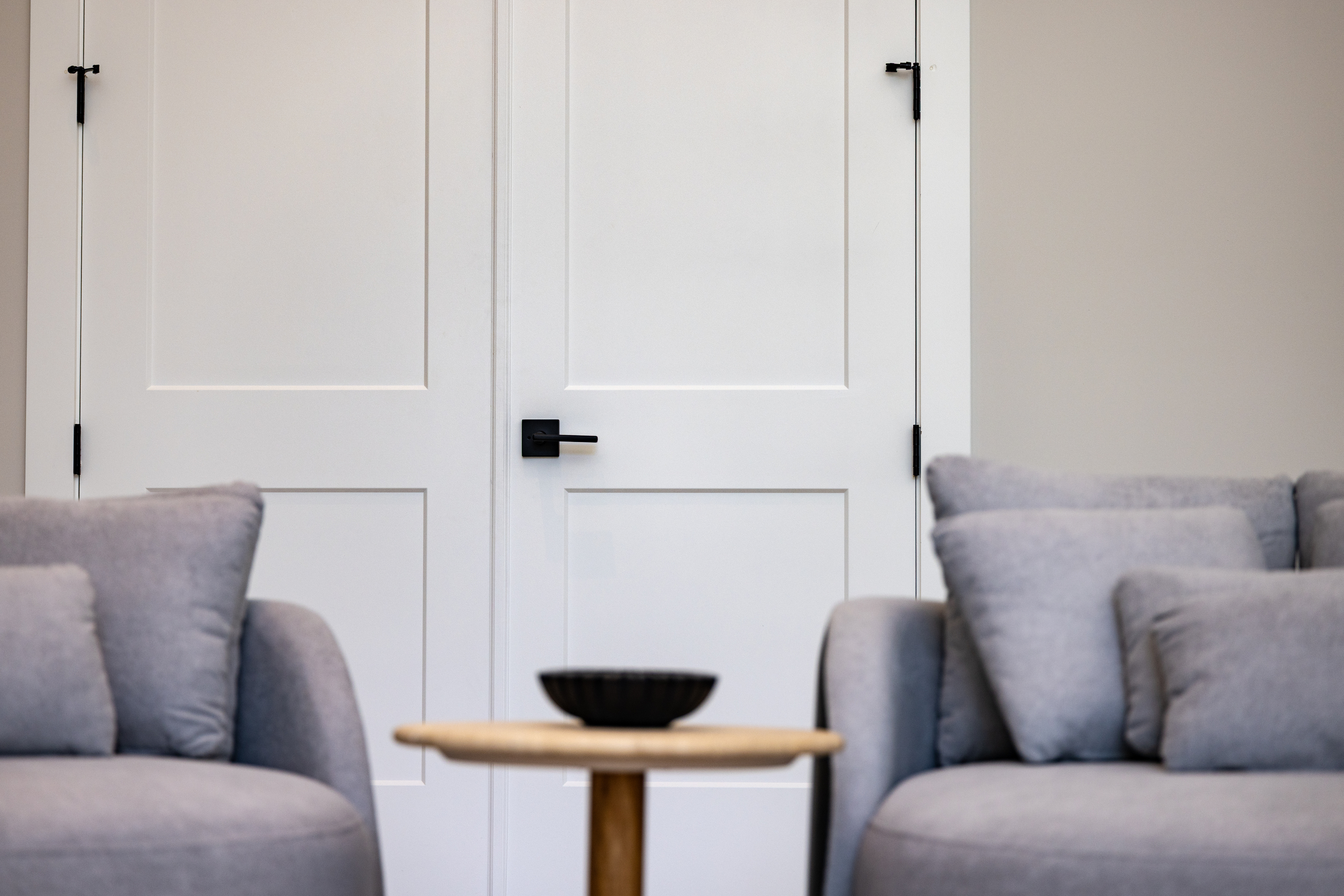 Modern living room with double white interior doors featuring black hardware, installed by 1st Choice Door & Millwork.