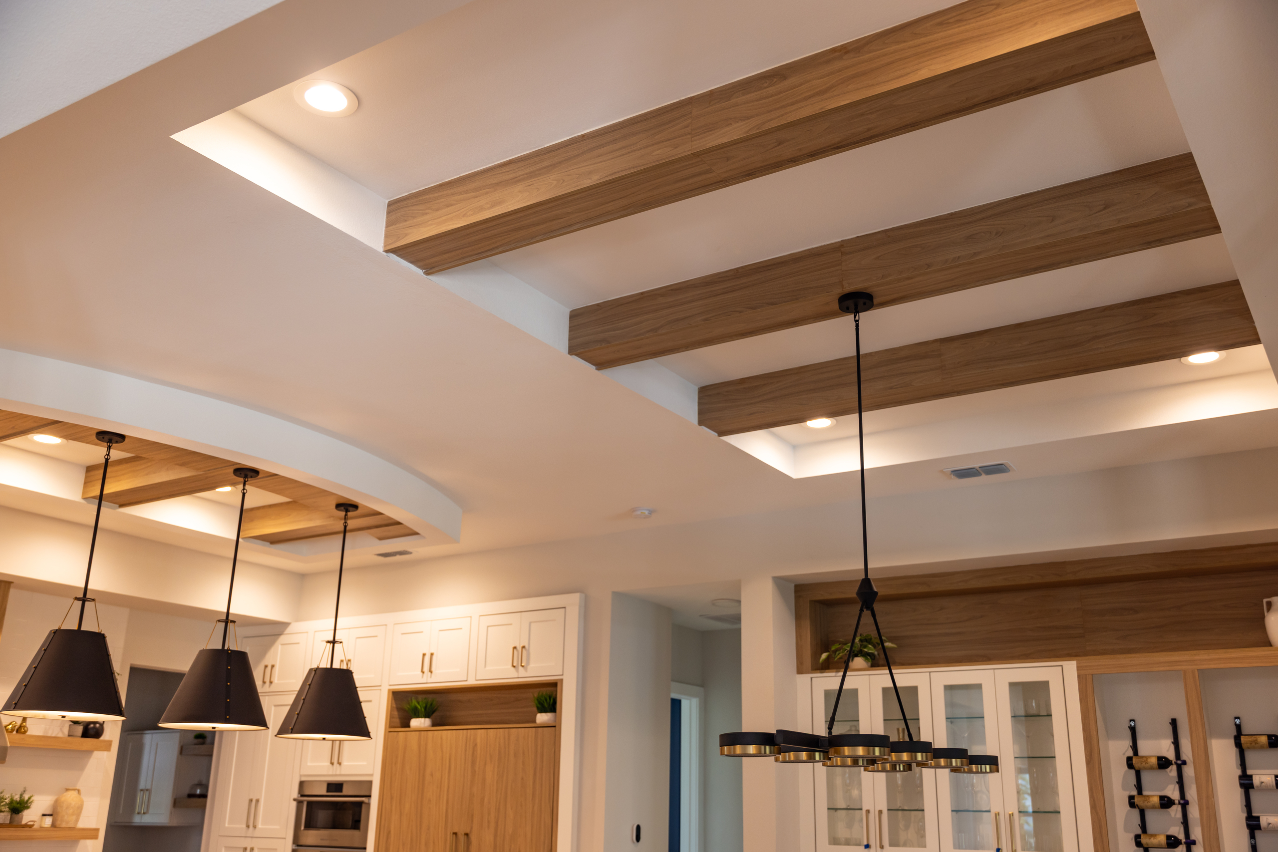 Close-up view of detailed ceiling beams and lighting in a modern kitchen, showcasing 1st Choice Door & Millwork craftsmanship.
