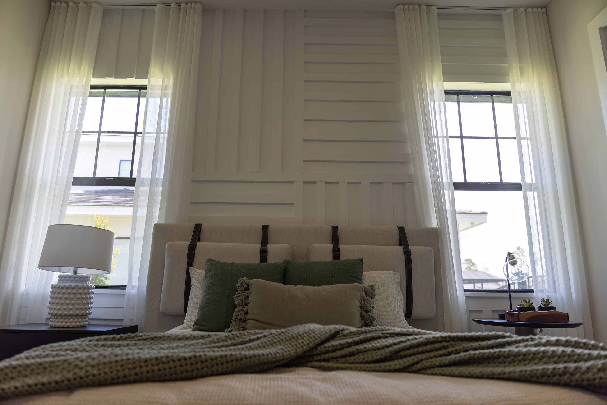 Bright bedroom with white accent wall and custom millwork paneling, designed and installed by 1st Choice Door & Millwork.