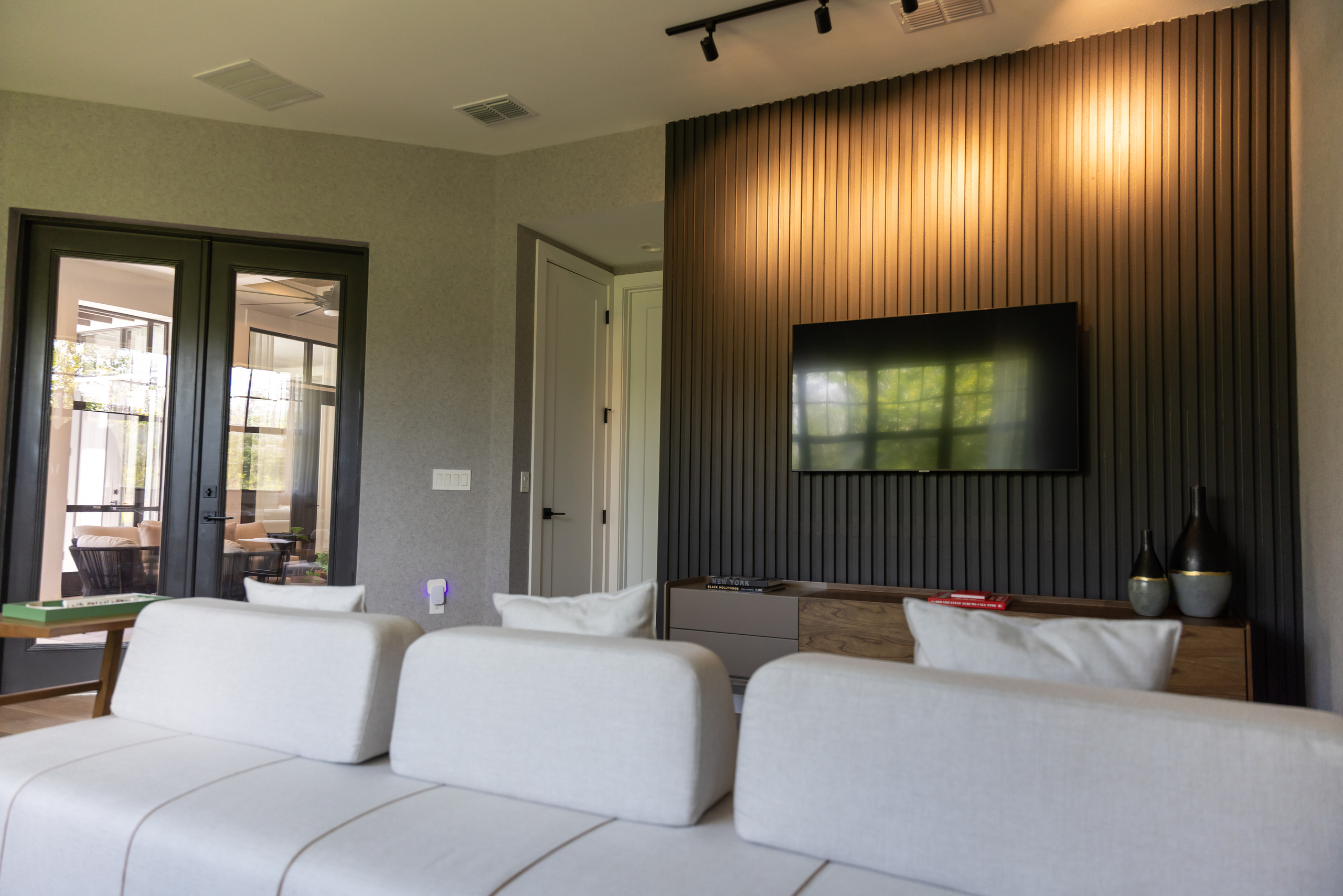 Modern living room with a black slatted accent wall, mounted TV, and custom millwork by 1st Choice Door & Millwork.