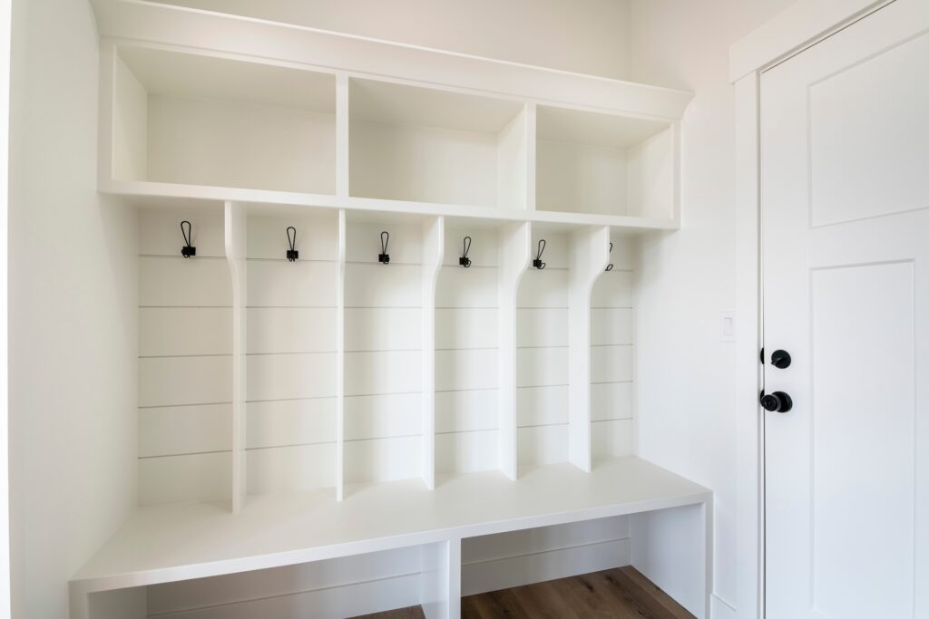A white mudroom with wood panelling and built-in storage