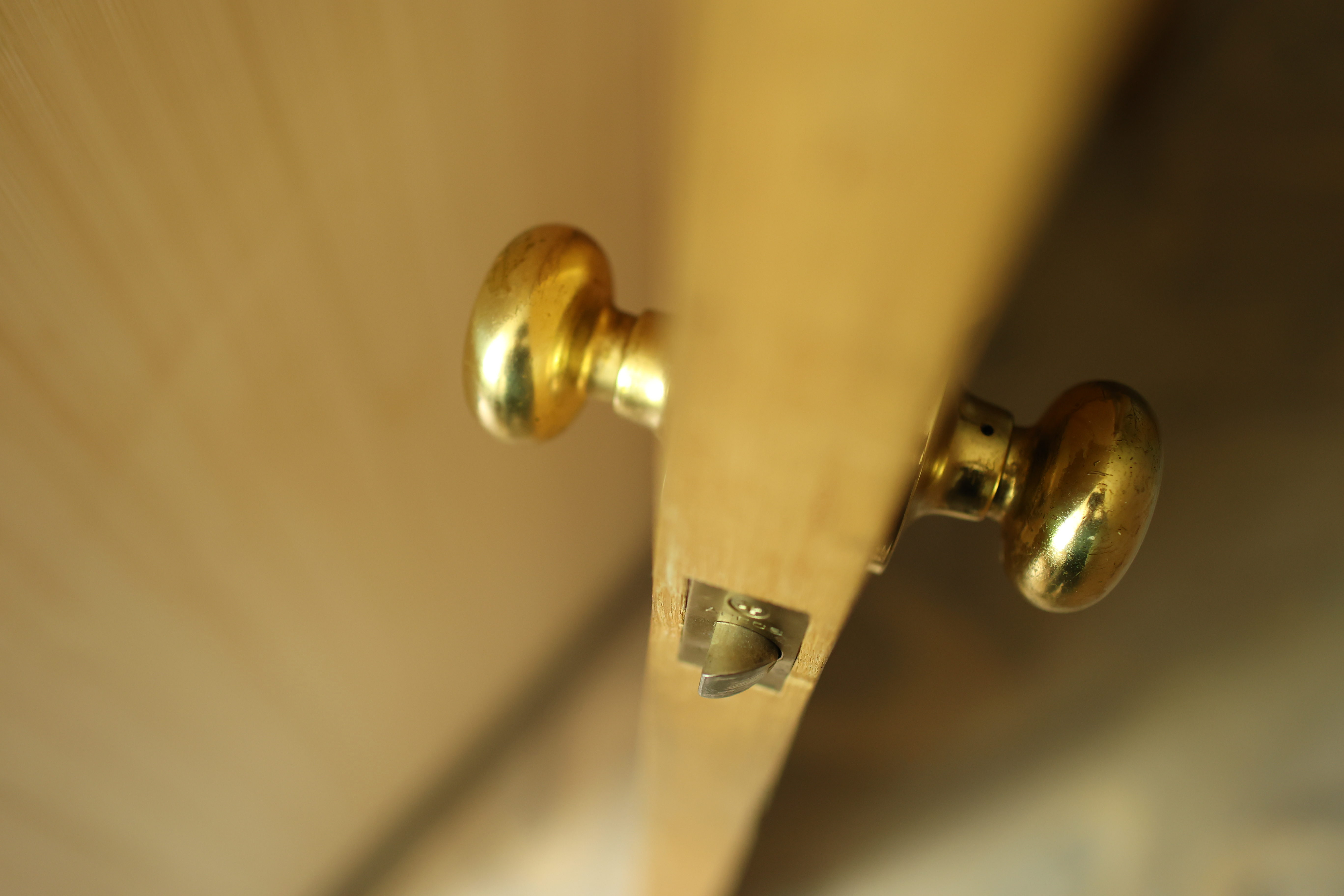 Close-up of a partially open interior door with polished brass round knobs and visible latch hardware.