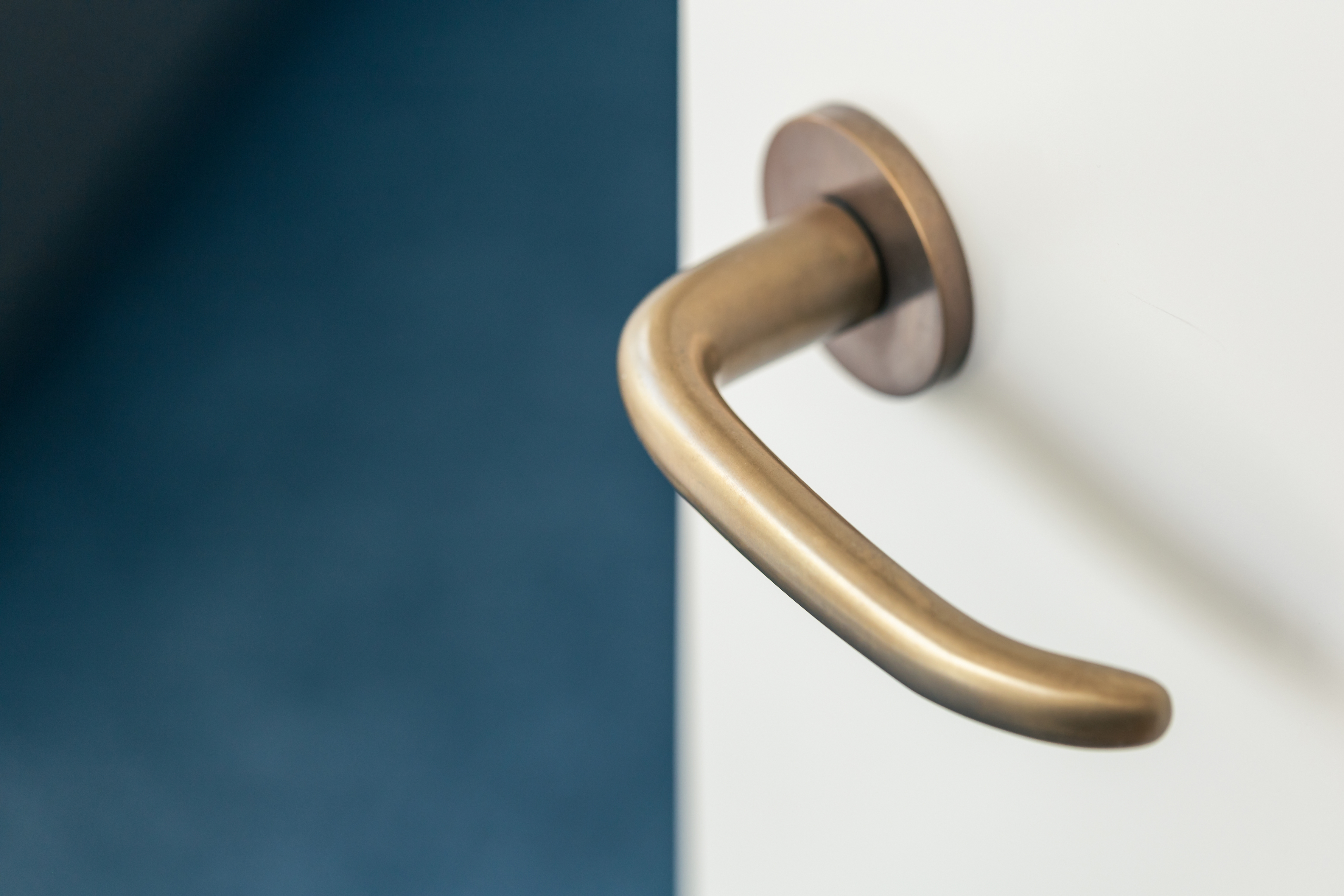 Close-up of a brushed brass interior door lever mounted on a white door.
